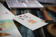 A flat lay of watercolor art and school supplies including paper and pencils.